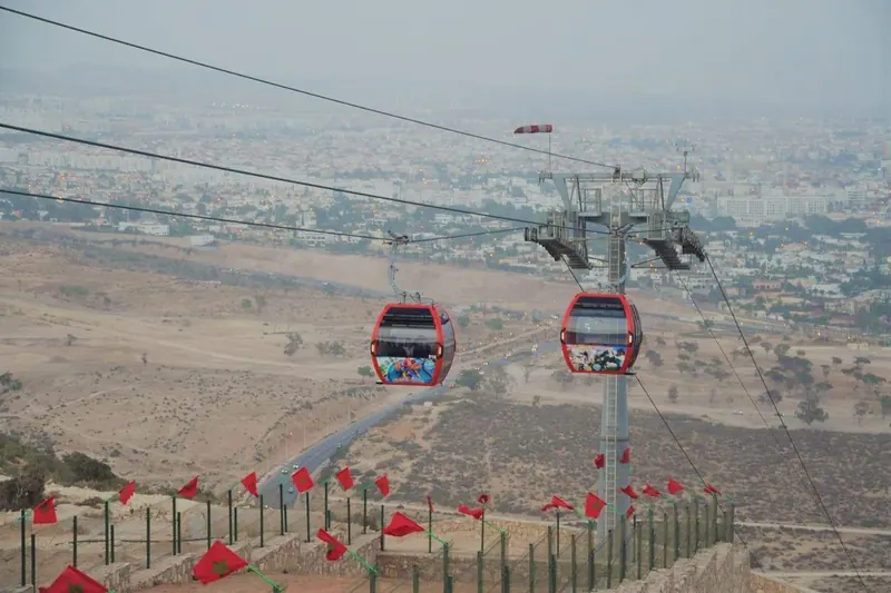 Red cable car cabins gliding above the slopes below Agadir's kasbah hill
