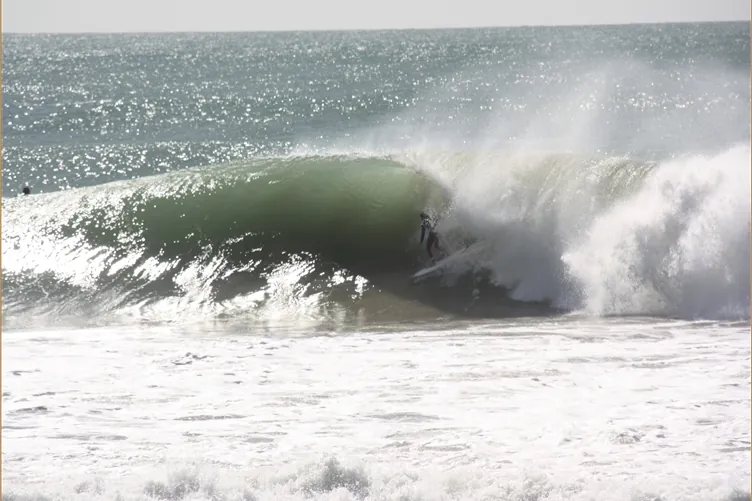A surfer tucked inside a large breaking wave off Taghazout
